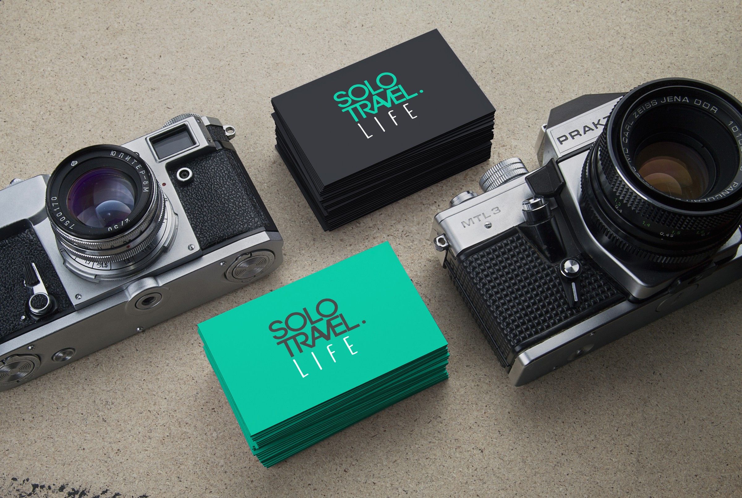 Turquoise and black business cards between two vintage cameras