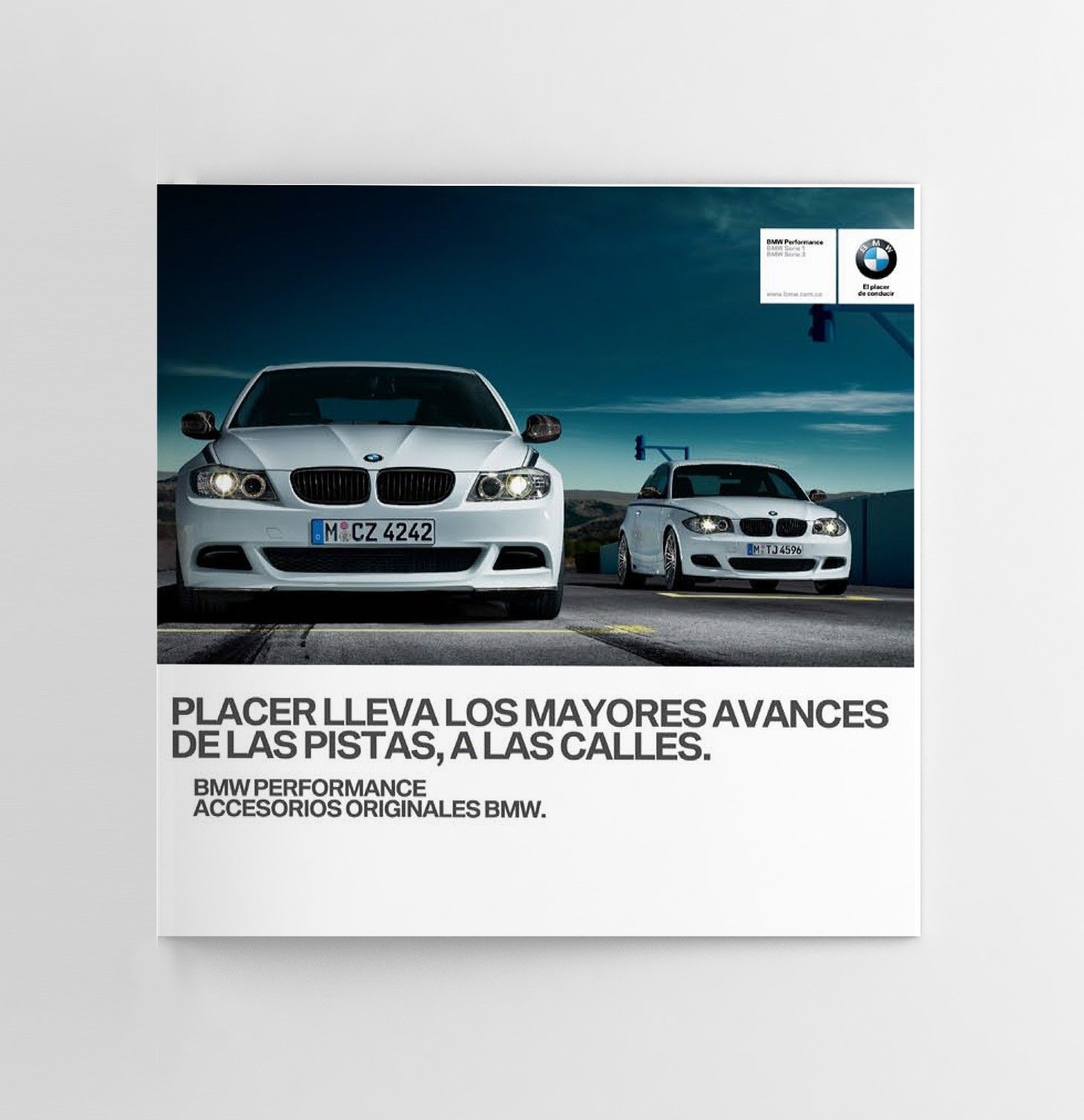 Brochure cover with two white BMWs on a track at dusk