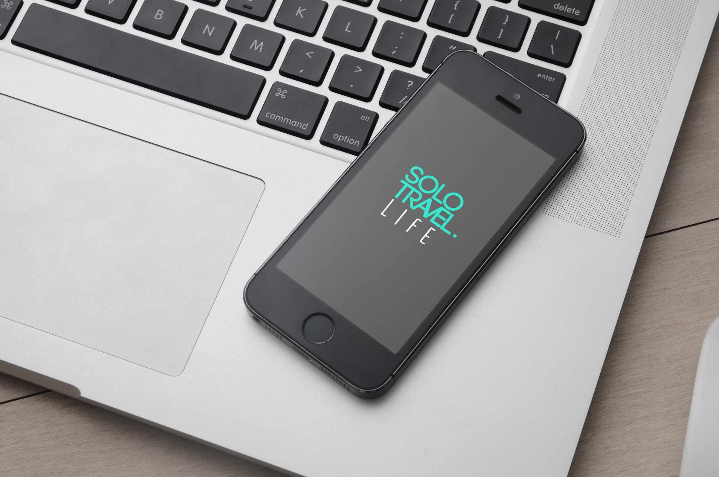 Phone showing the logo, resting on a laptop