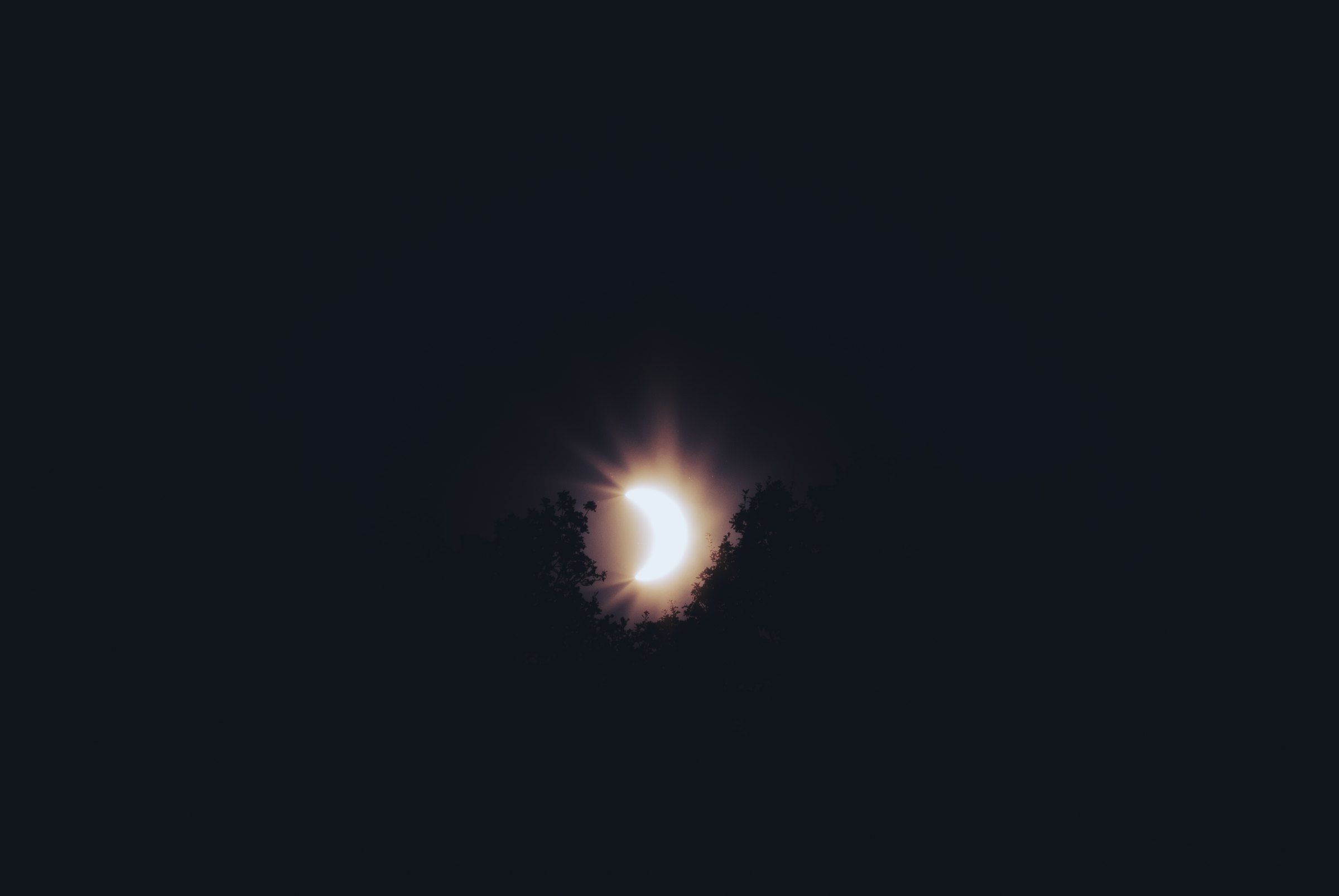 The sun reduced to a glowing sliver in a dark sky during an eclipse