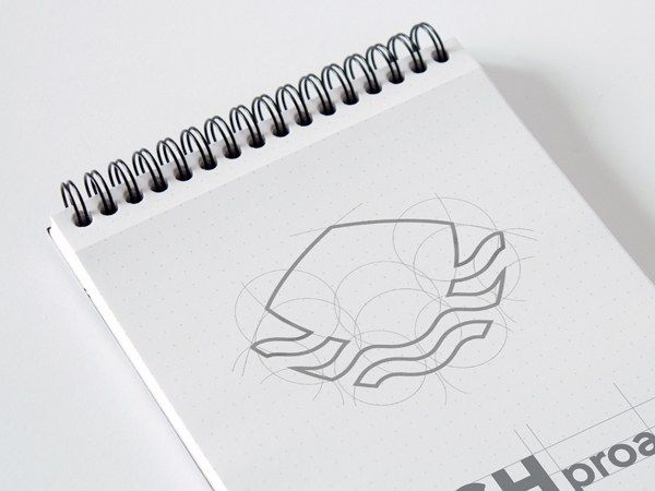 Construction sketch of the FISHproa boat-bow symbol on a spiral notepad